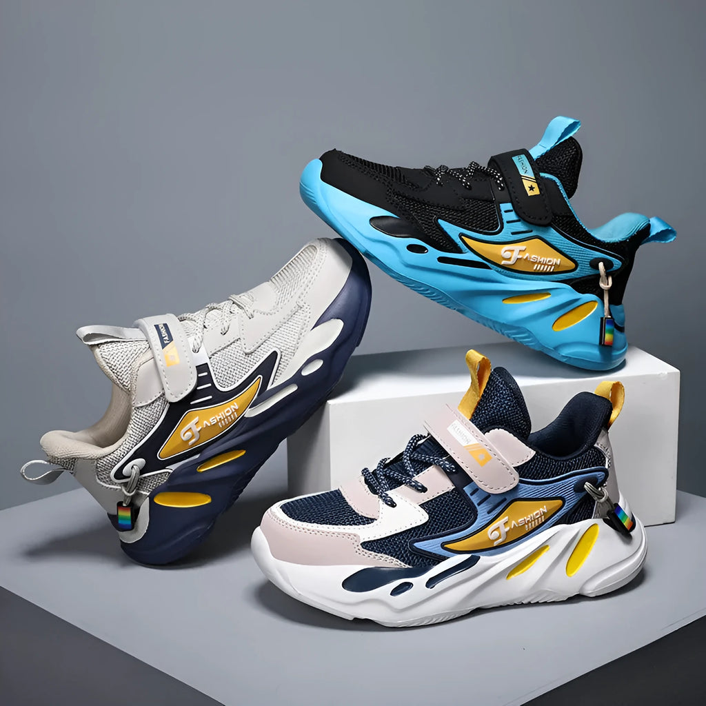 Boys sports running shoes in dark blue with a mesh upper and Velcro strap, shown on a hard ground surface.
