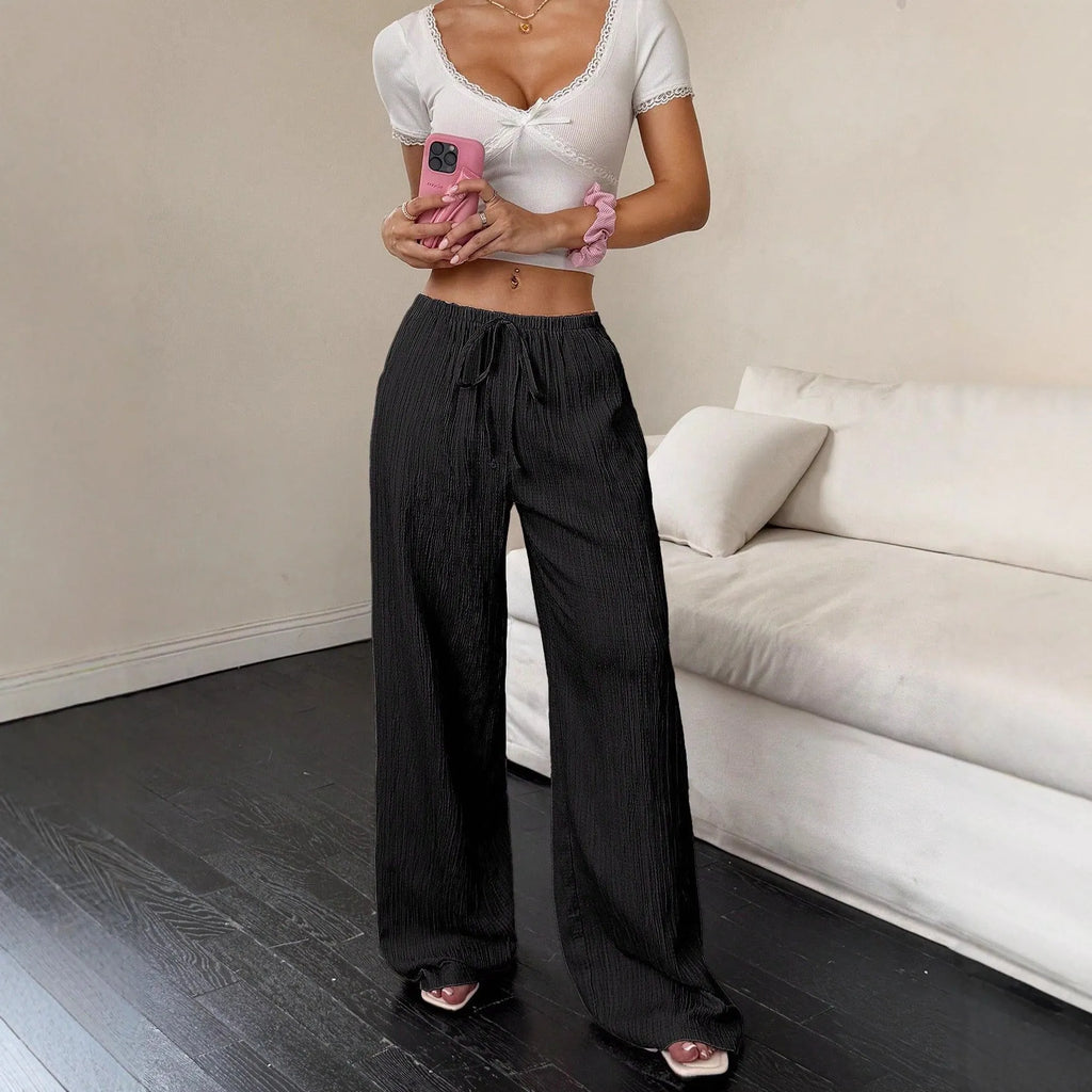 Women's black wide-leg trousers with lace-up waist detail and flowy silhouette