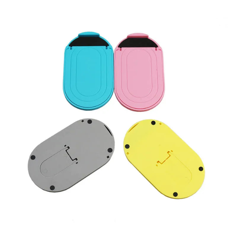 Adjustable plastic mobile phone stand in multiple colours on a table, holding a smartphone at an angle