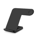 Black wireless charging pad on a wooden desk with smartphone placed on top, showing non-slip silicone base.
