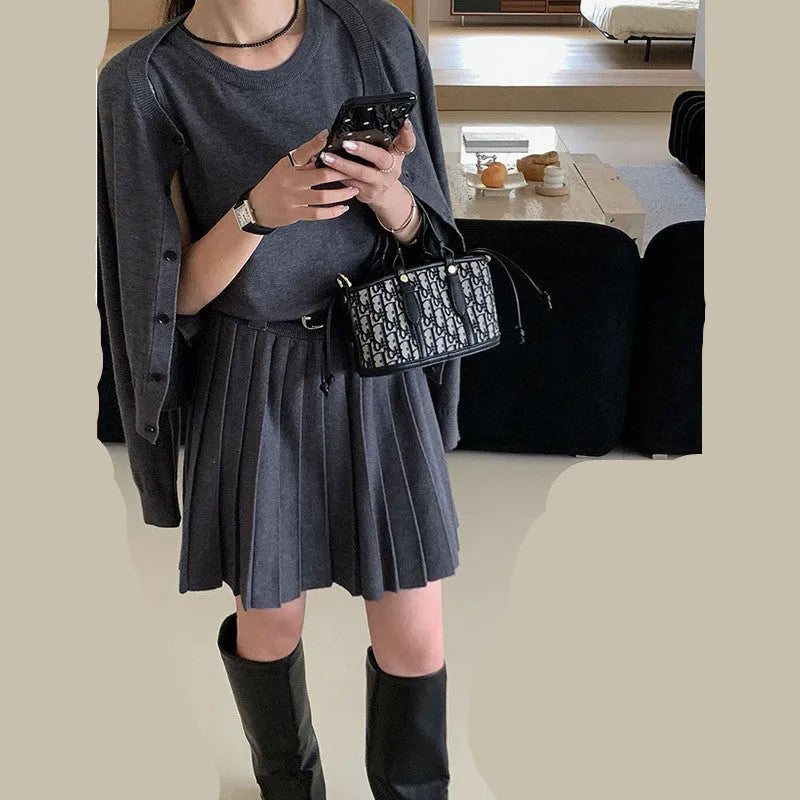 Women's black knitted two-piece set with long-sleeve cardigan, pleated vest skirt, 3D pattern, and a belt.