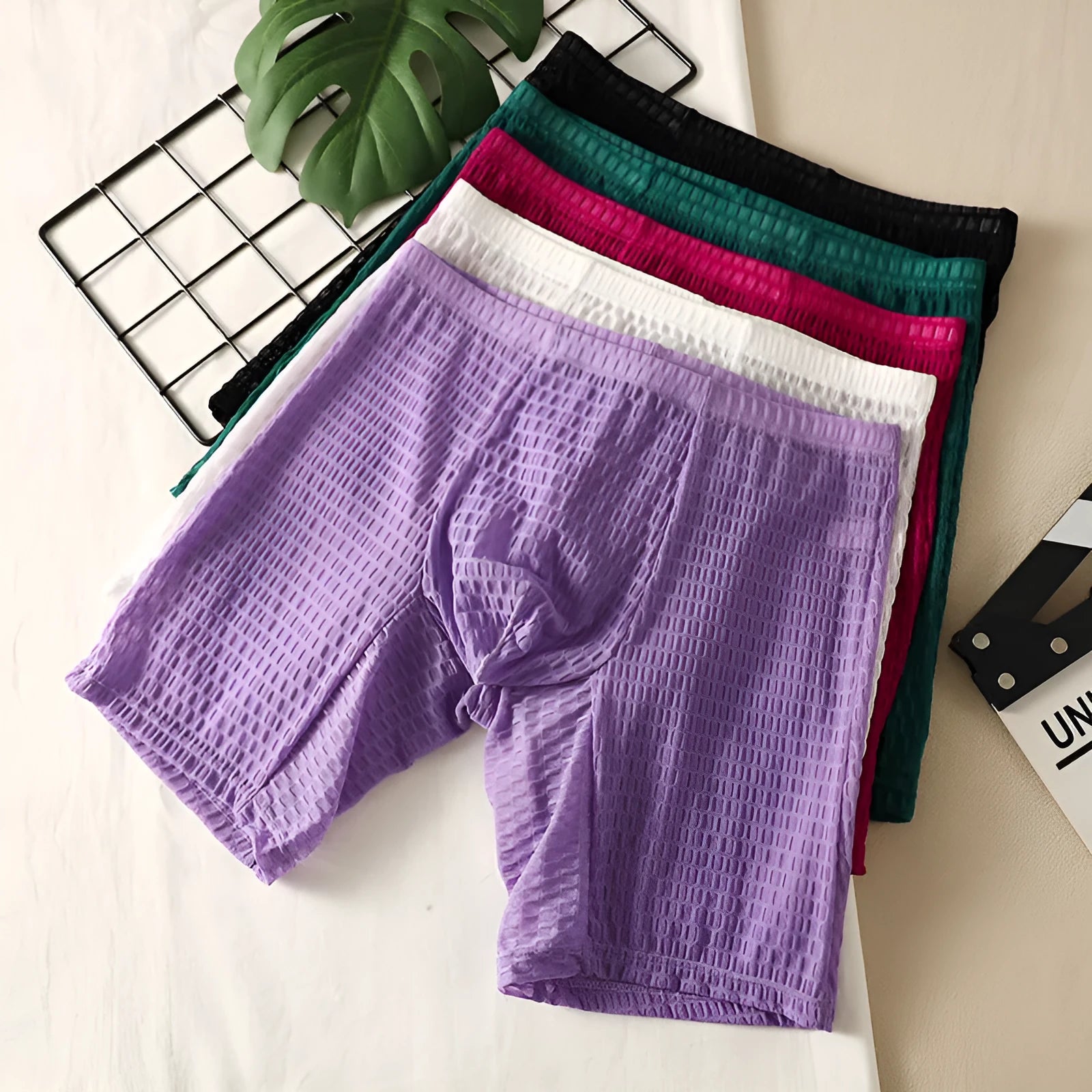 Men's lace boxer shorts in a lengthened hip lifting design, shown in one of five solid colours.