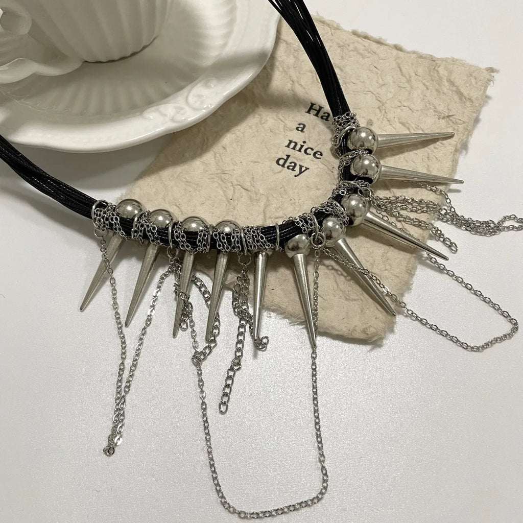 Leather necklace with winding round beads, metallic rivet details, and a long tassel in an electroplated finish.