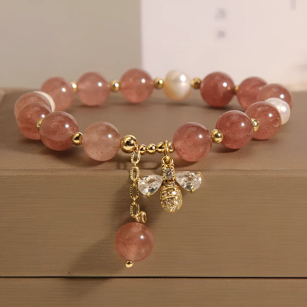 Women's adjustable bracelet with pink strawberry quartz stones, white freshwater pearls, and zircon accents on a wrist.