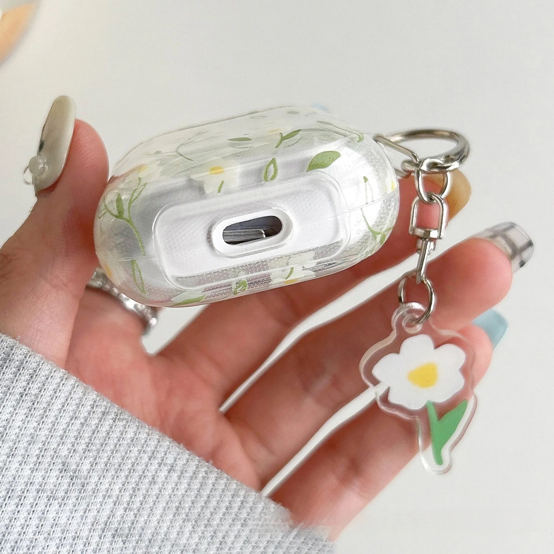 Transparent white floral patterned soft TPU protective case for Apple AirPods on a table.