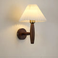 American retro rubber wood and fabric wall lamp in walnut finish on a wall.