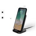 Dark grey vertical wireless charging stand for smartphones on desktop
