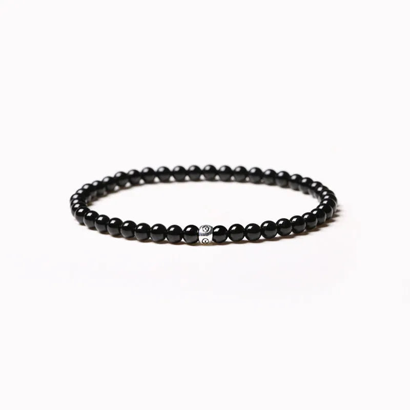A unisex beaded bracelet with small 4mm obsidian, blue San, and black agate stones in geometric shapes.