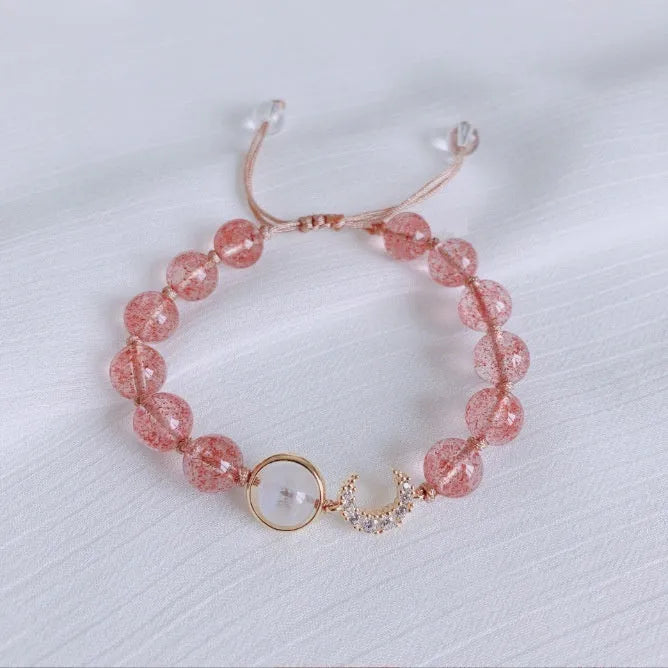 Handmade strawberry quartz crystal bracelet with peach blossom design on a wrist.