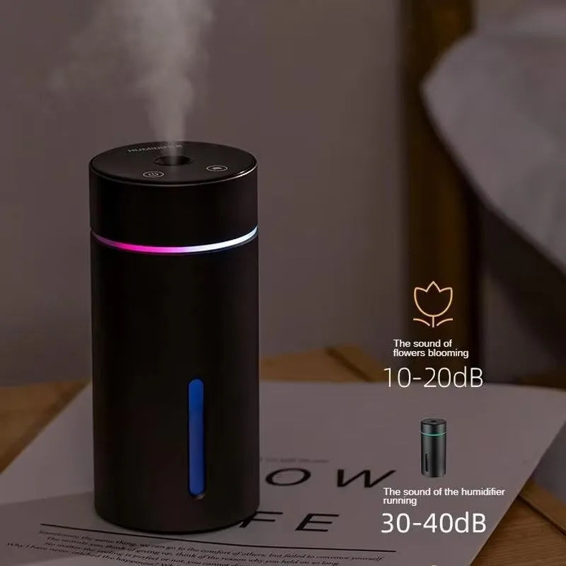 Black aluminium car humidifier diffuser with night light on a desk next to USB cable
