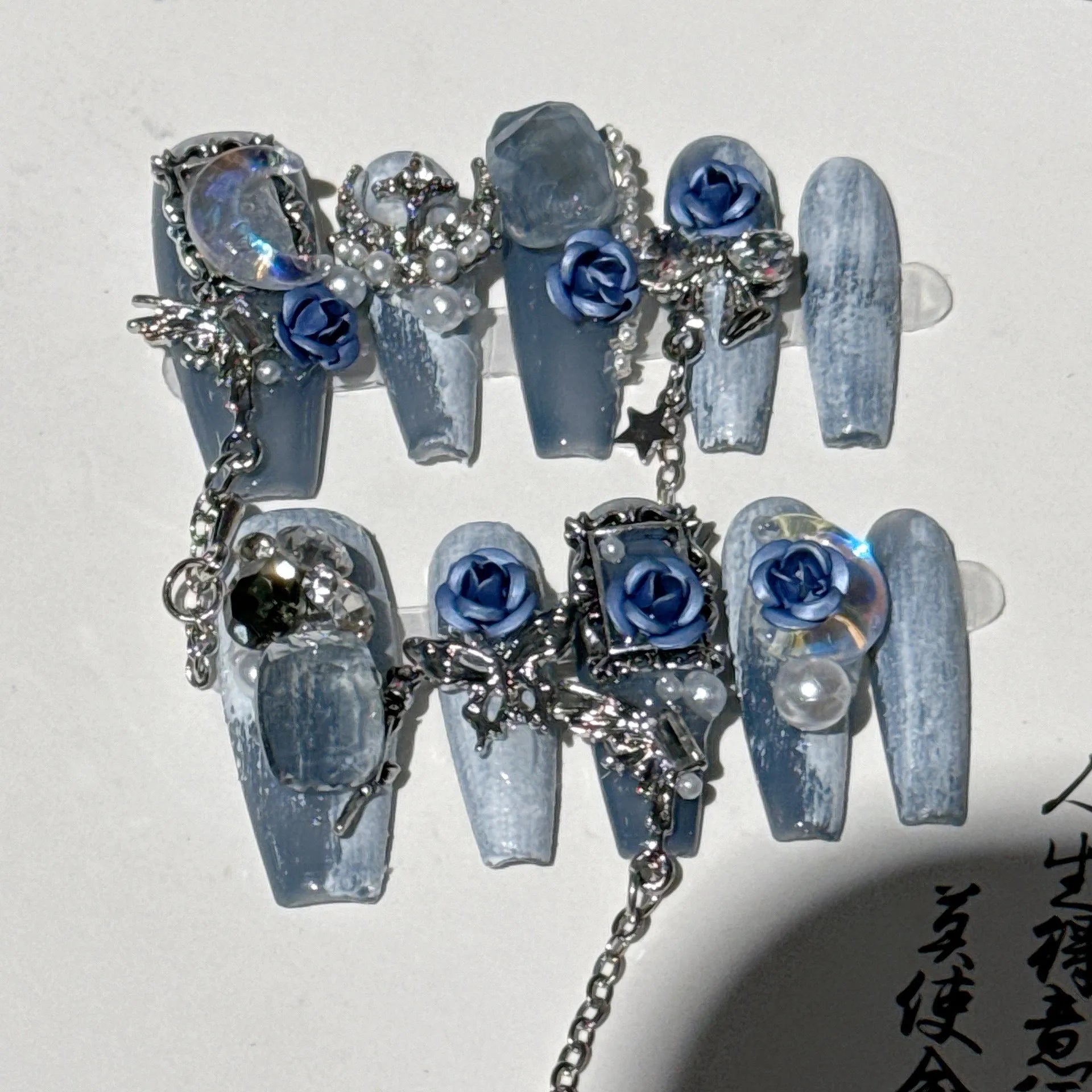Heavy industry night blue false nails with ornate twinkling rose and tulip flower pattern.