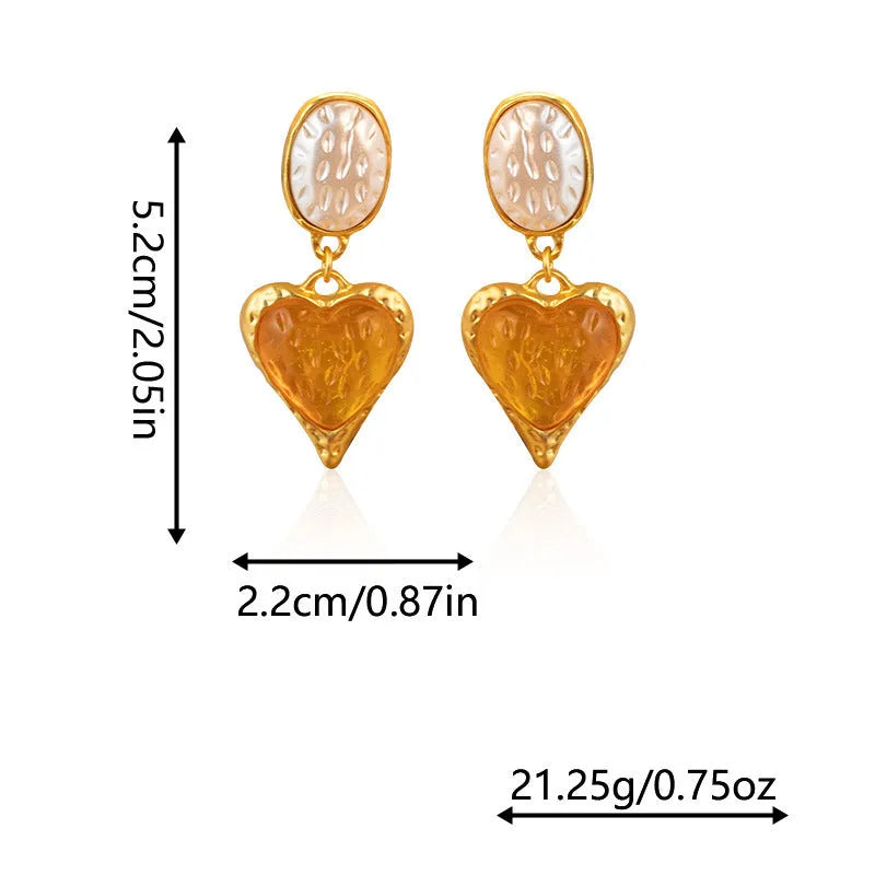 Close-up of a pair of textured needle-pleated oval heart stud earrings in an alloy metal, showing colour options.