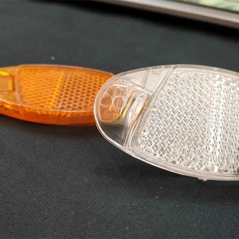 Yellow and white plastic bicycle spoke reflectors showing size of 7.2cm by 3.5cm.