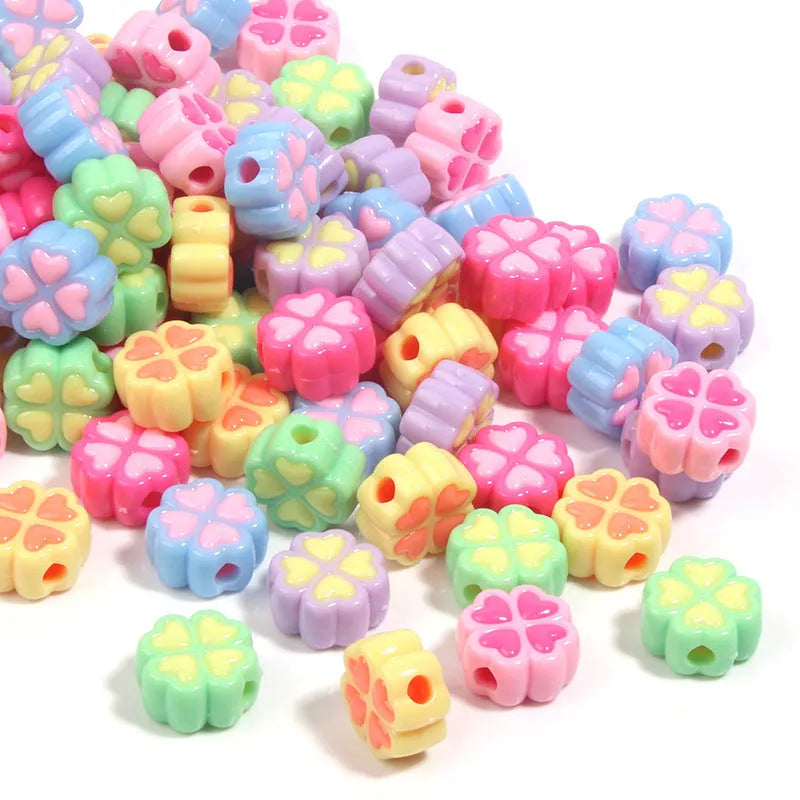 Frosted acrylic four-leaf clover shaped beads in mixed colours on white background