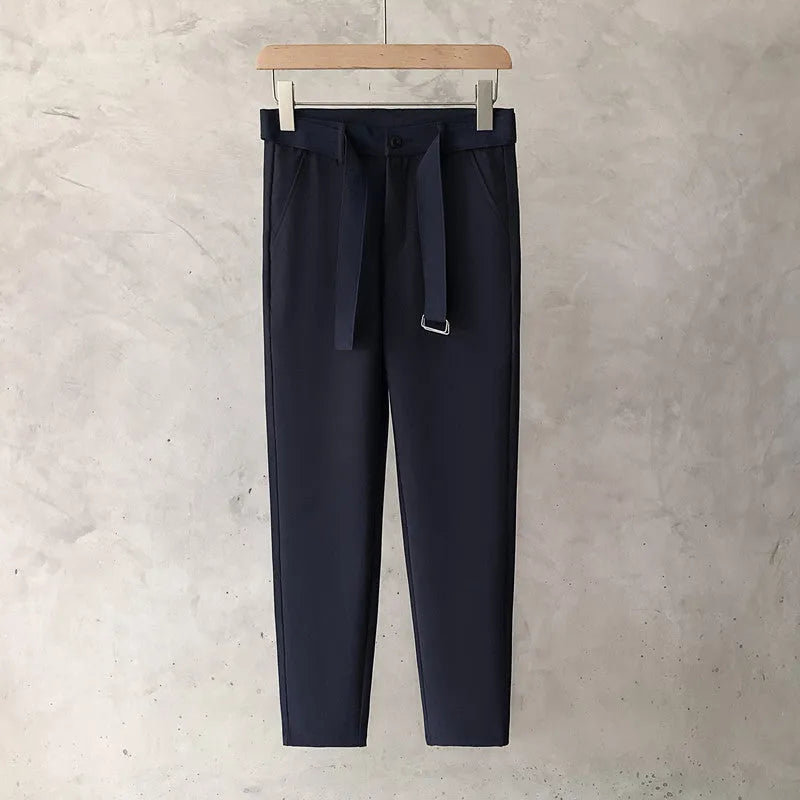 Boy wearing slim straight tapered wool trousers in a grey colour, showing the straight leg opening and belt loops.