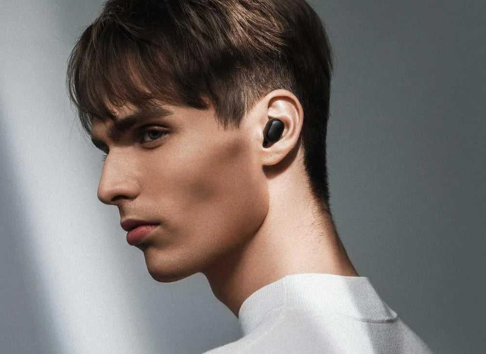 Redmi AirDots black true wireless earbuds next to their compact white charging case.