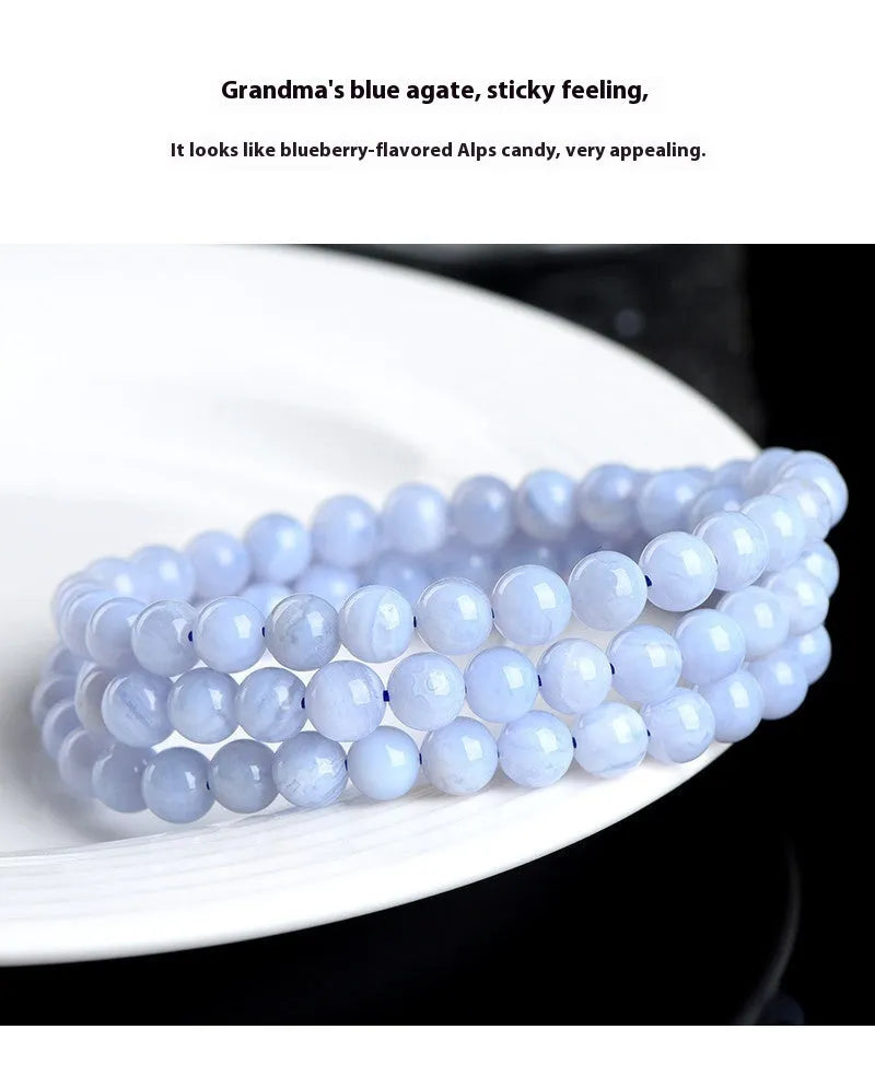 Blue striped agate bead bracelet with Ruyi charm on a wrist.