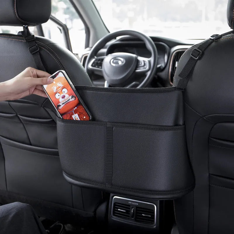 Black leather car seat storage bag with carbon fibre pattern, shown fitting between car seats.