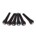 Six matt black ebony folk guitar string nails on a grey background