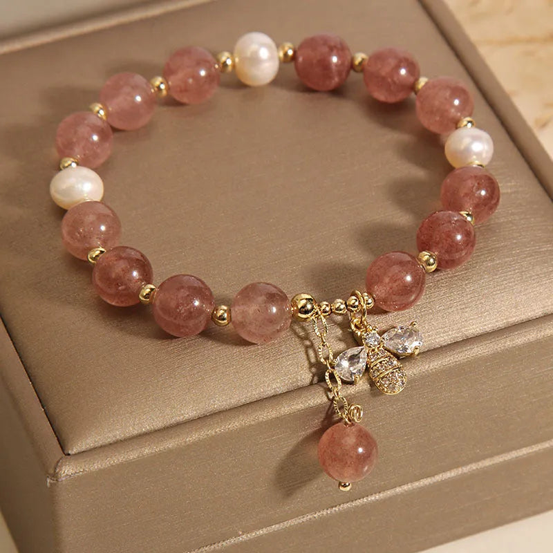 Women's adjustable bracelet with pink strawberry quartz stones, white freshwater pearls, and zircon accents on a wrist.