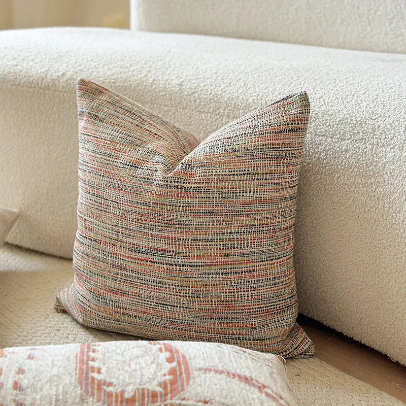 Jacquard woven paisley pattern pillow cover in amber colours on a sofa.