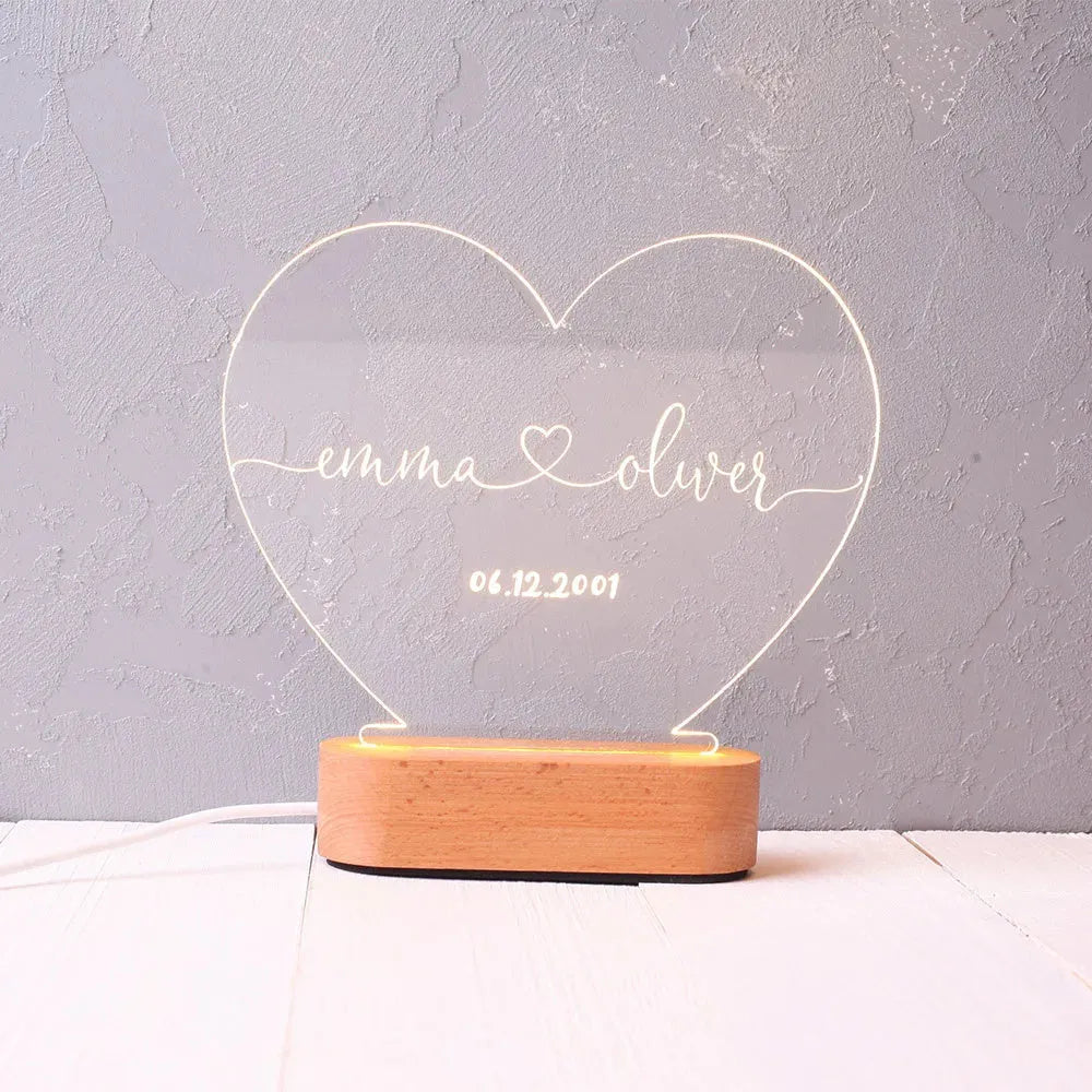 Custom acrylic night light with engraved names illuminated by LED base on bedside table