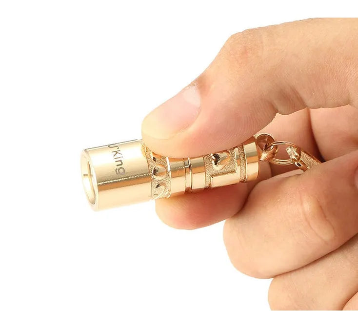 Gold zinc alloy LED flashlight attached to a keyring for outdoor and emergency use.