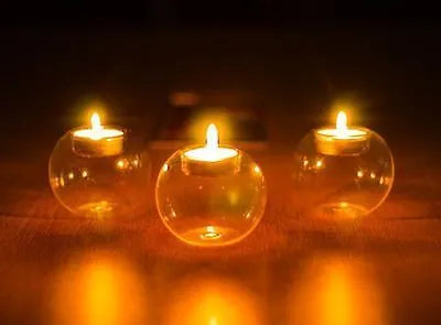Handmade round hollow glass candle table centrepiece on a wooden surface.