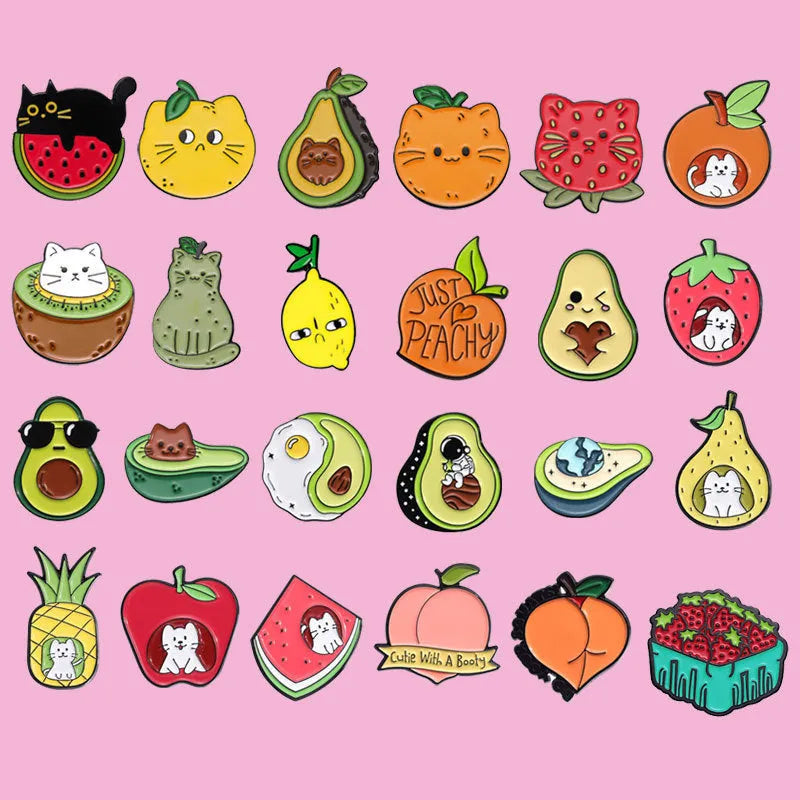 Colourful cartoon fruit and letter design metal brooch on a fabric background.