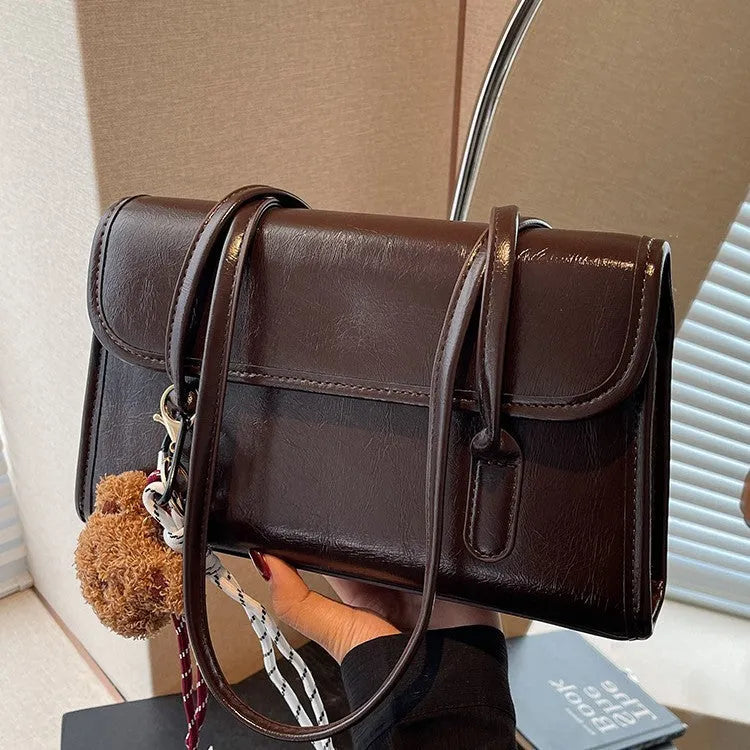 Brown structured women's PU shoulder bag with double straps, a pendant, and a horizontal square shape.
