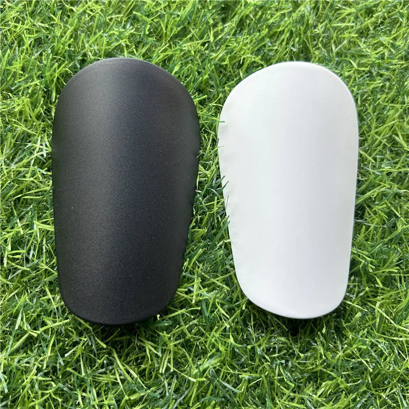Extra small black and white plastic football shin guards for junior players.
