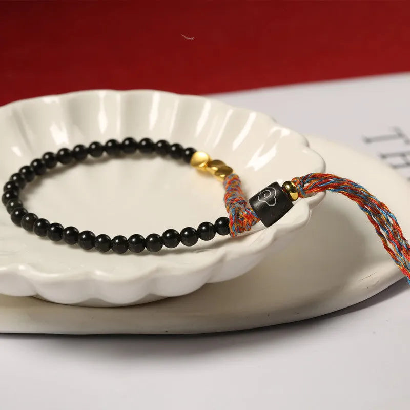 Hand-woven obsidian stone bracelet on a wrist, showing its dark colour and 4mm width.