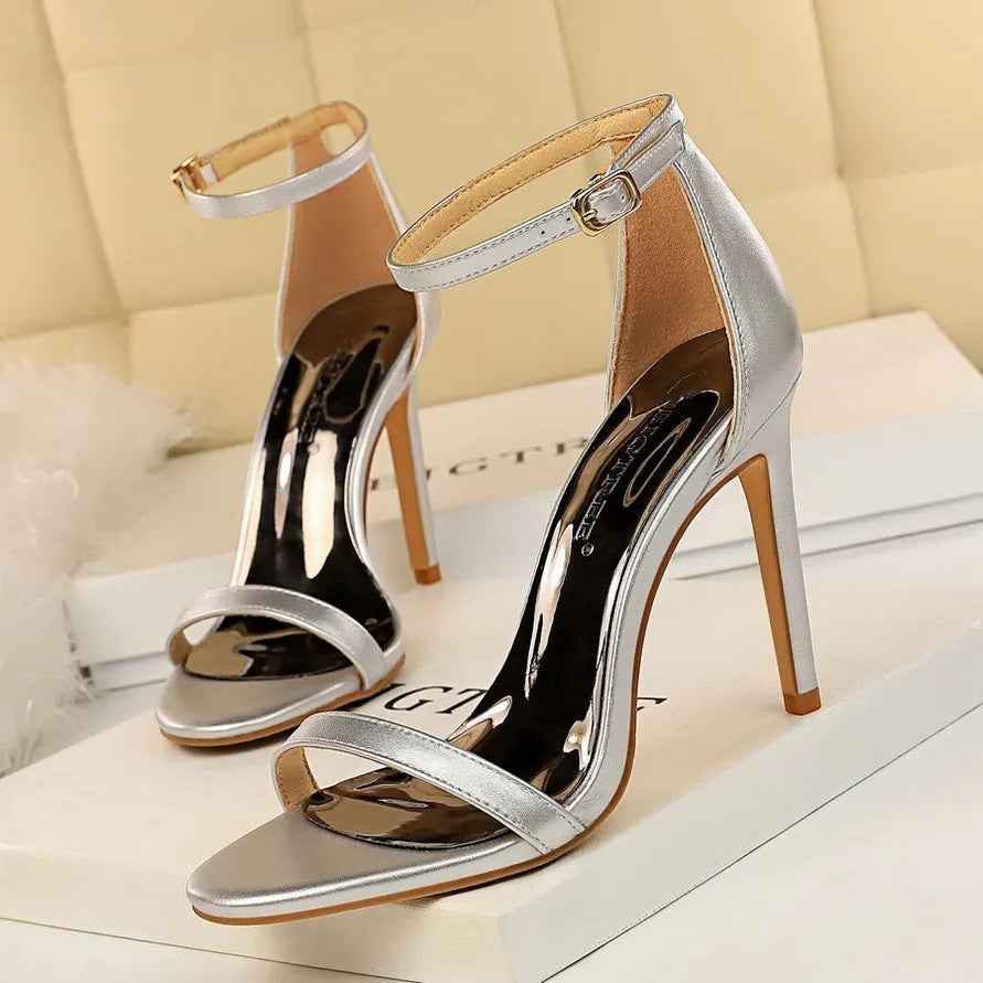 Open toe ankle-strap high heels in artificial PU leather with buckle fastening, shown in multiple colours.