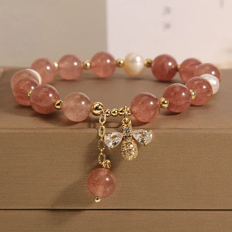 Women's adjustable bracelet with pink strawberry quartz stones, white freshwater pearls, and zircon accents on a wrist.