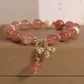 Women's adjustable bracelet with pink strawberry quartz stones, white freshwater pearls, and zircon accents on a wrist.