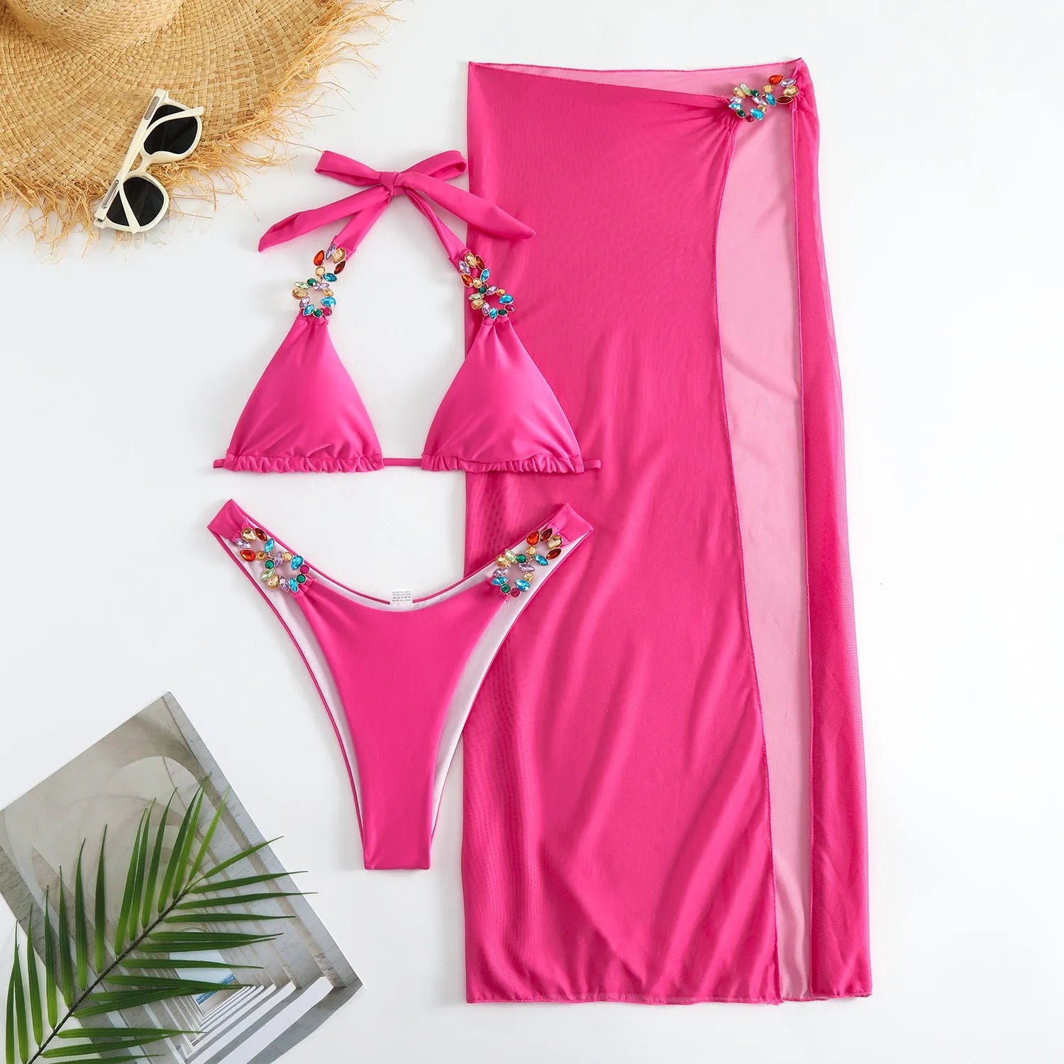 Rose red three-piece swimsuit with bikini top, briefs, and a light diamond mesh cover-up skirt laid flat.