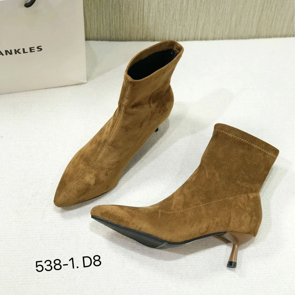 Black women's pointed toe Martin ankle boots with a high stiletto heel on a model.