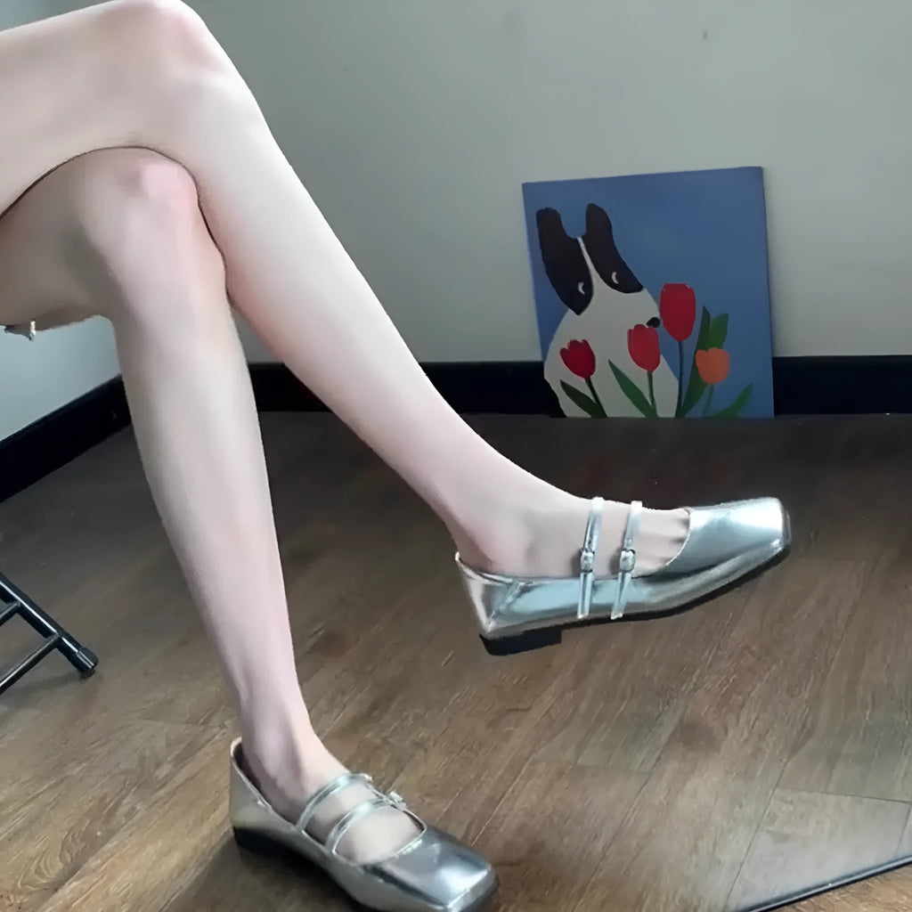 Women's silver leather Mary Jane flats with a cross-buckle strap and round toe.