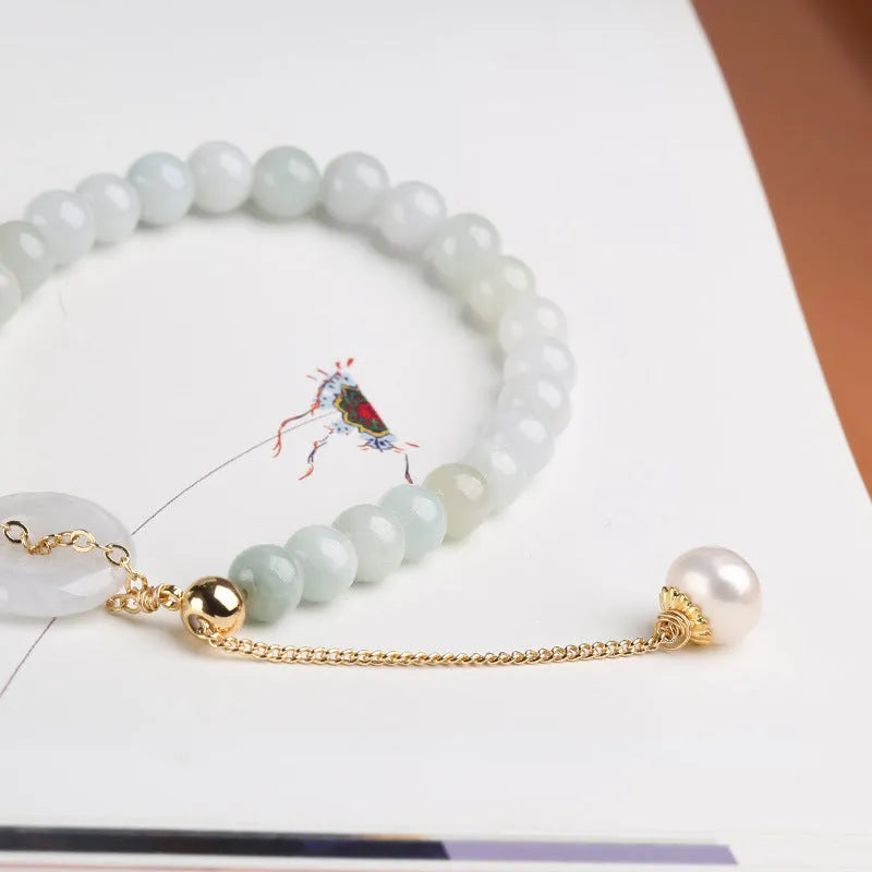 Close-up of a women's bracelet with a jade peace symbol buckle on a string of freshwater pearls.