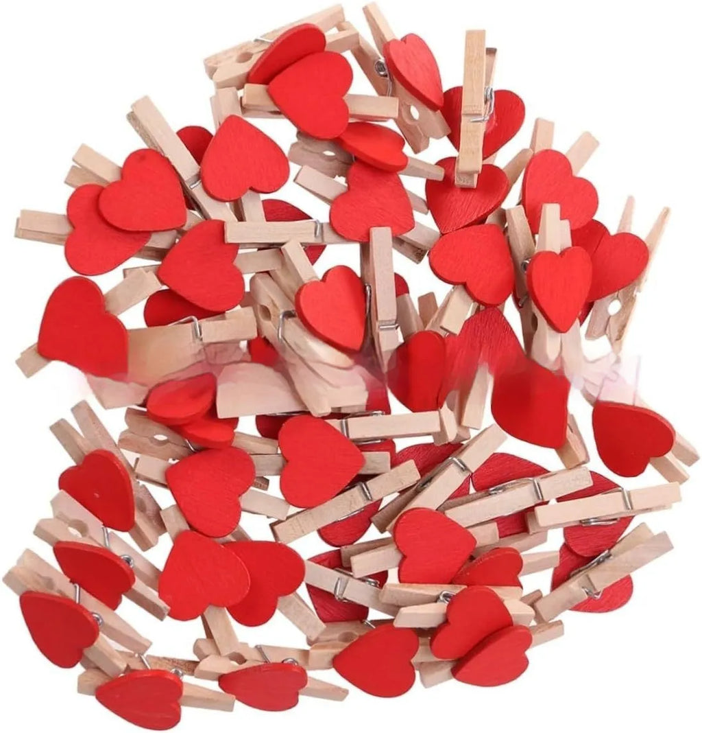 Set of five handmade solid wood heart-shaped clips in red, white, and rose red on a plain surface.