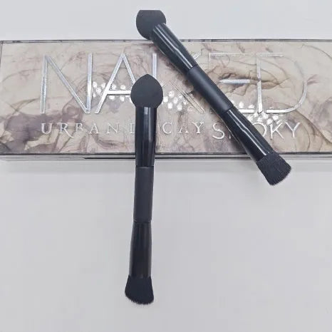 Double-headed concealer brush with tapered bristles and a miter sponge on a long black wooden handle.