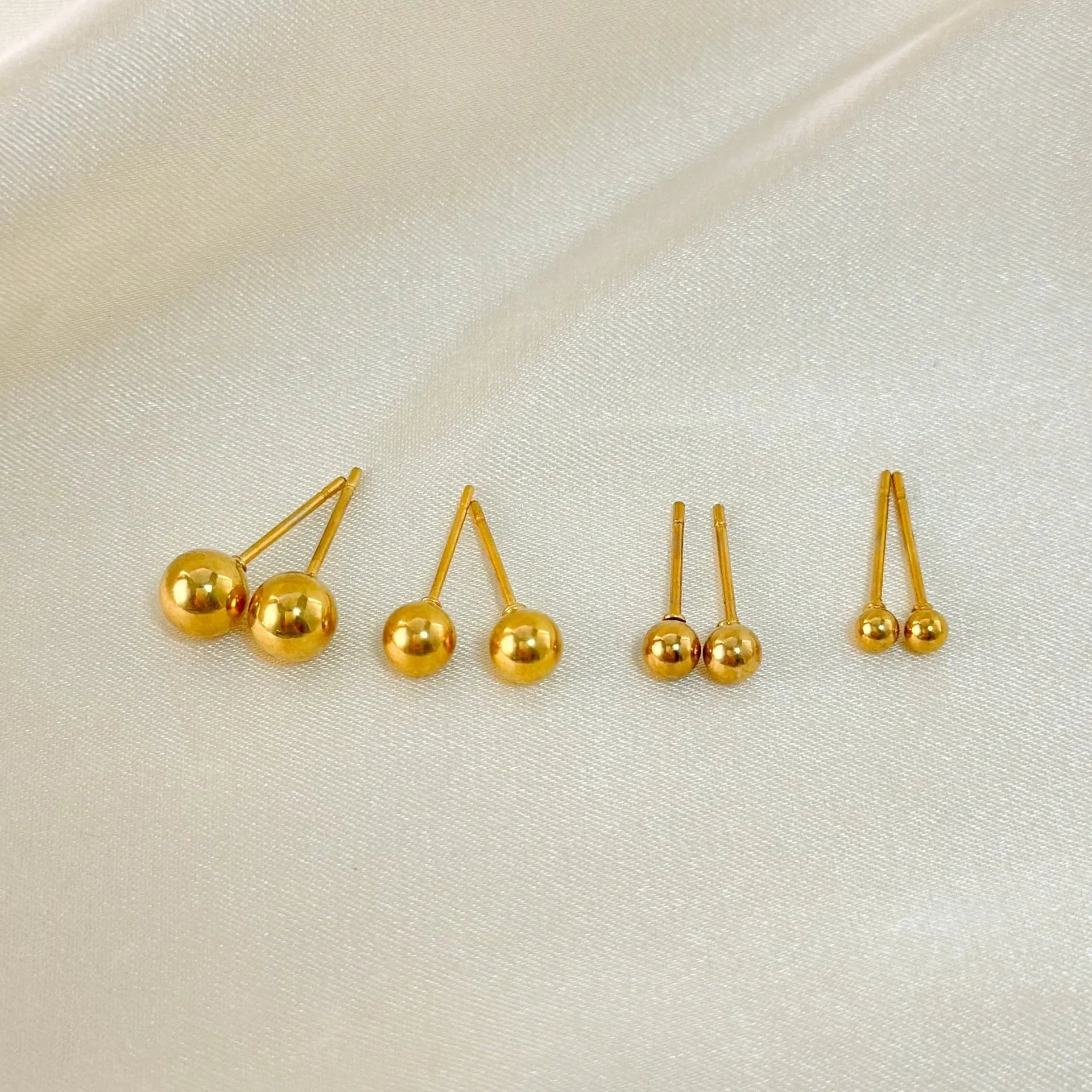 Stainless steel ball stud earrings in gold and silver, shown in 3mm, 4mm, 5mm, and 6mm sizes