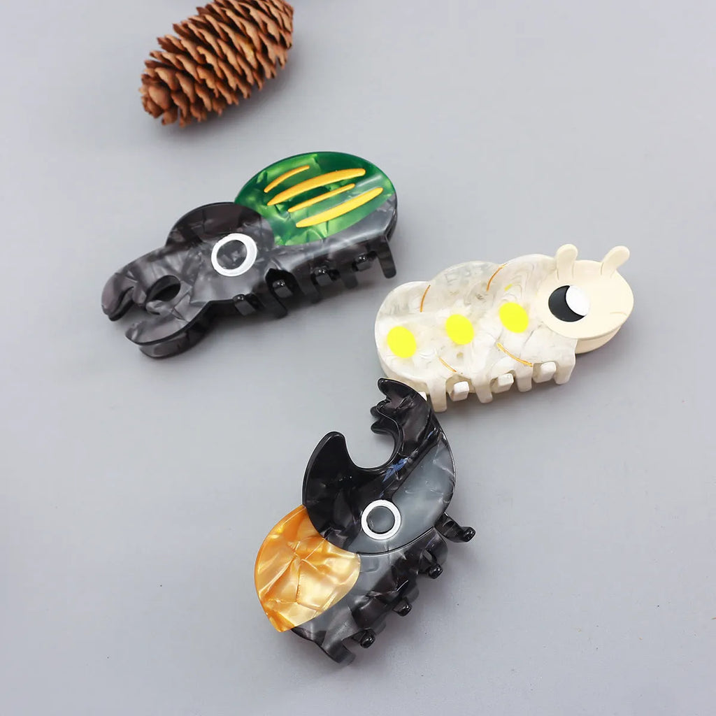 Handmade cartoon insect biology grip on cellulose acetate sheet in green beetle, orange beetle, or white caterpillar design.
