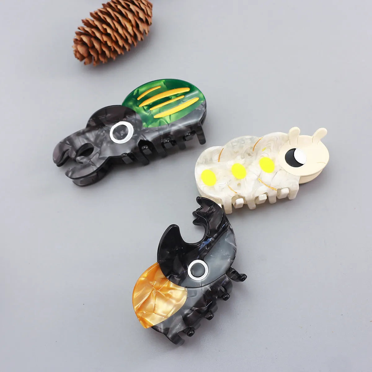 Handmade cartoon insect biology grip on cellulose acetate sheet in green beetle, orange beetle, or white caterpillar design.