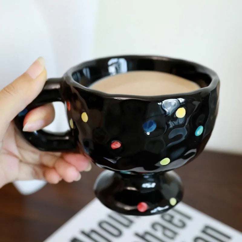 Hand-pinched irregular shaped ceramic mug in a solid colour on a table