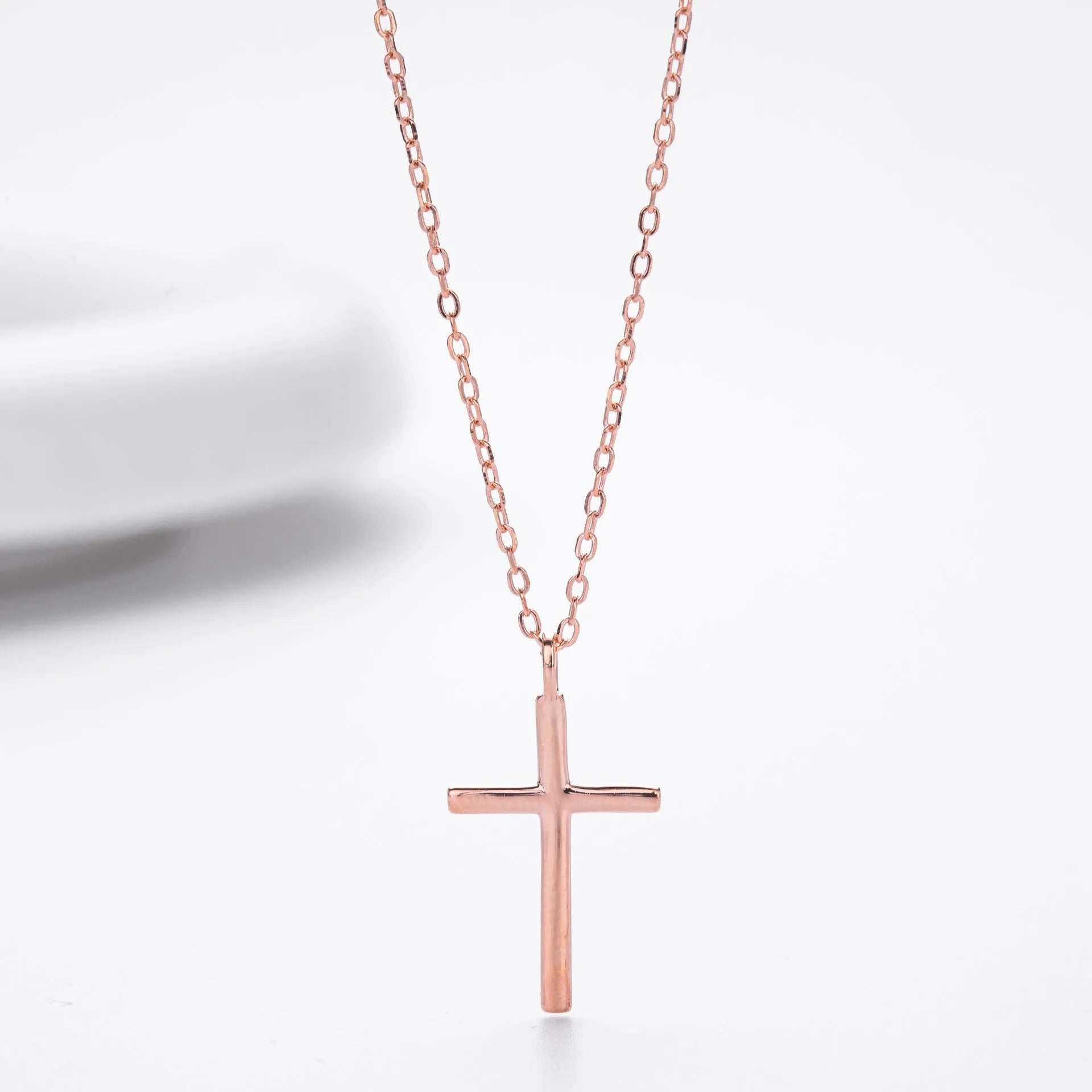 Simple glossy cross pendant on a sterling silver O-chain necklace, shown in gold, platinum, and rose gold finishes.