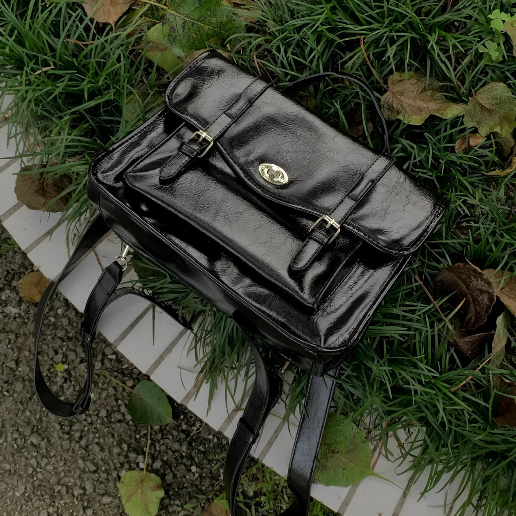 Black college style messenger bag with oil wax leather-look PU material, showing front and strap.