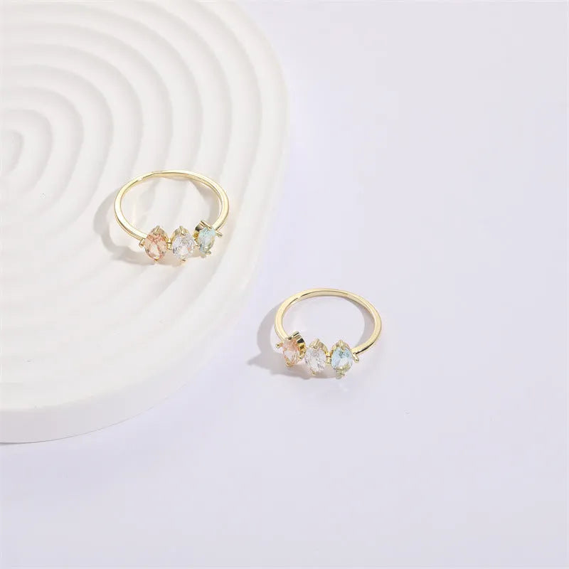 Women's gold-coloured ring with a horse eye design and three coloured zircon stones on a geometric band.