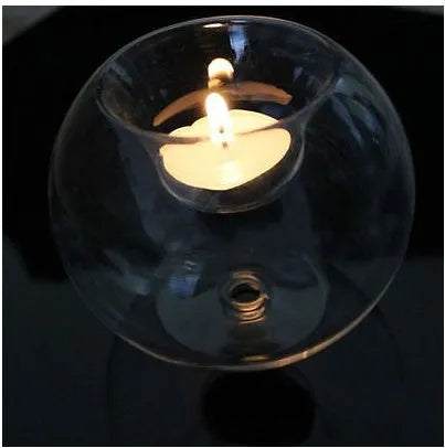 Handmade round hollow glass candle table centrepiece on a wooden surface.