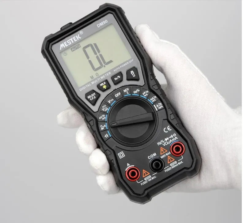 DM90A digital multimeter with test leads on a workbench, showing its large display and rotary function selector.